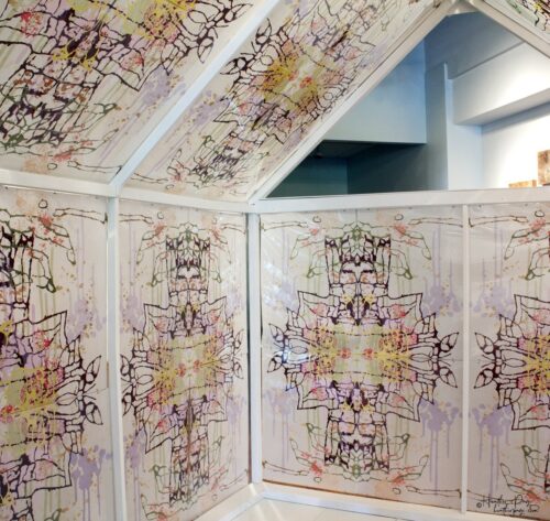 Interior of Daily Dose Installation by Heather Page, an art installation of a 7' by 6' by 6' peaked house frame covered in colorful abstract silkscreen prints