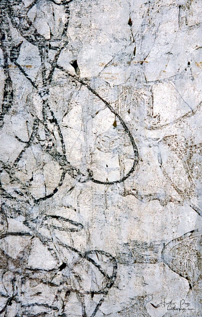 Back of Fantasie by Heather Page, a 60” by 15” monoprint on paper of looping calligraphic text in black & silver on a silver ground that hangs from the ceiling