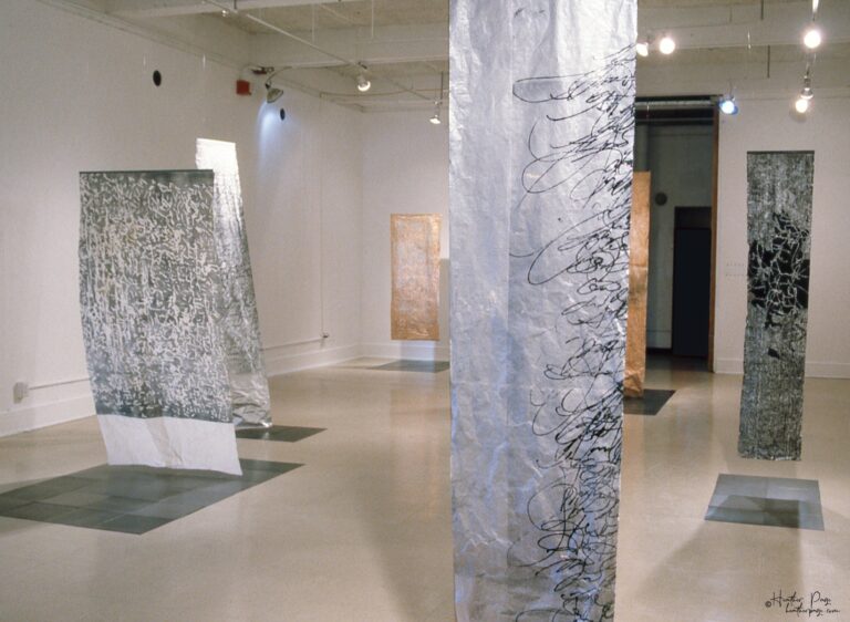 Reverb III by Heather Page, an art installation of large-scale prints on paper suspended from the ceiling of calligraphy, glyphs, and patterns found in nature