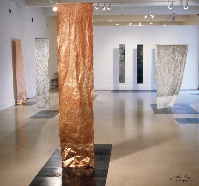 Reverb III by Heather Page, an art installation of large-scale prints on paper suspended from the ceiling of calligraphy, glyphs, and patterns found in nature