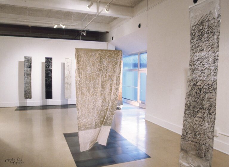 Reverb III by Heather Page, an art installation of large-scale prints on paper suspended from the ceiling of calligraphy, glyphs, and patterns found in nature