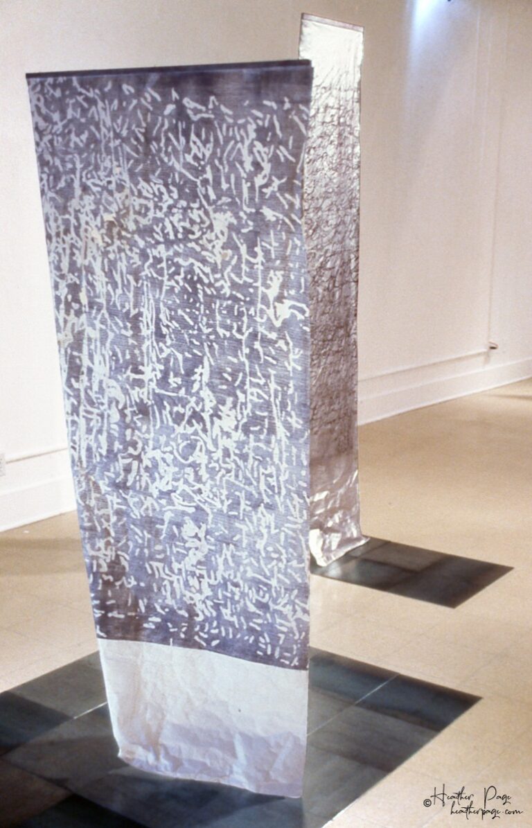 Rondo by Heather Page is a 74” by 38” relief print, rubbing, and drawing on paper of calligraphic marks and looping text dancing over a dappled silver ground